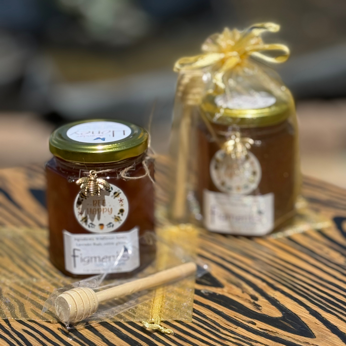 Two jars of honey with a dipper on a wooden surface