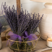 Bouquet of lavender in a gold wire basket with a purple bow on a wooden surface.